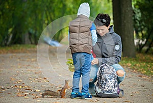 Little boy with his mother feeding a squirrel at a park