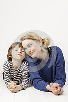 Little boy and his mother lying down close to each other on the white background.