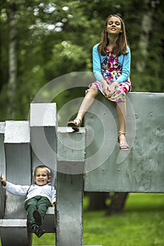 Little boy with his older sister on the Playground in the Park. Fun.
