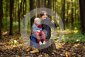 Little boy with his young mother playing during stroll in the forest