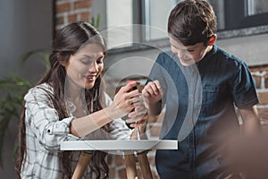 Little boy and his young mother sitting on floor at home assembling a coffee table