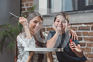 Little boy and his young mother sitting on floor at home leaning on a coffee table