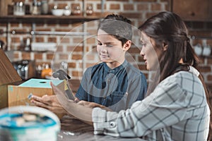 Little boy and his young mother working on a wooden birdhouse