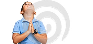 Little boy hispanic kid wearing casual clothes begging and praying with hands together with hope expression on face very emotional