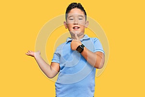 Little boy hispanic kid wearing casual clothes showing palm hand and doing ok gesture with thumbs up, smiling happy and cheerful