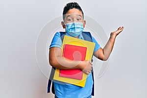 Little boy hispanic kid wearing medical mask going to school celebrating achievement with happy smile and winner expression with