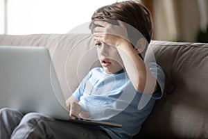 Little boy hocked by inappropriate content, looking at computer screen.
