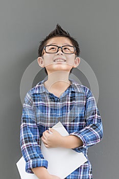 Little boy hold the book with hands having happiness against the gray wall