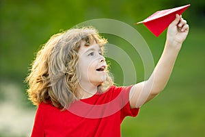 Little boy hold paper planes. Toy airplane in children hands outdoor. Happy boy leaning and throwing yellow paper