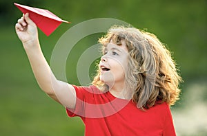 Little boy hold paper planes. Toy airplane in children hands outdoor. Happy boy leaning and throwing yellow paper