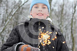 Little boy hold sparkler in forest