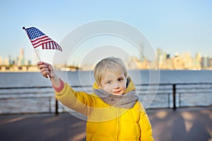 Little boy holding the American flag on the background skyscrapers of Manhattan