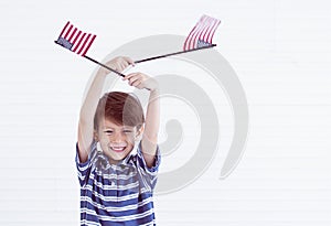 A little boy holding american flags