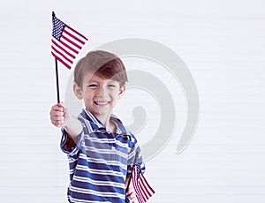 A little boy holding american flags