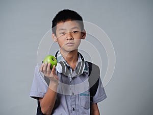 Little boy holding apple on grey background