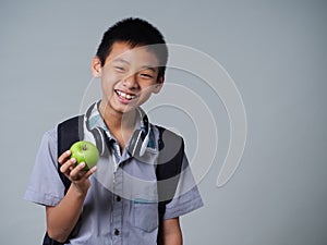 Little boy holding apple on grey background