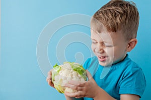 Little Boy Holding Broccoli in his hands on blue background, diet and exercise for good health concept