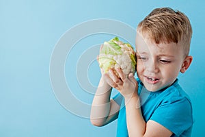 Little Boy Holding Broccoli in his hands on blue background, diet and exercise for good health concept