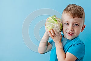 Little Boy Holding Broccoli in his hands on blue background, diet and exercise for good health concept