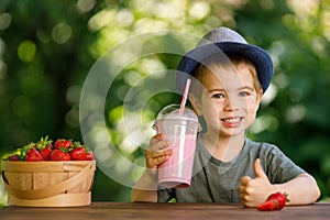 little boy holding disposable plastic glass of strawberry milkshake