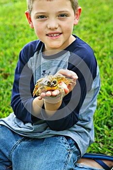 Little boy holding a frog