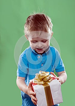 A little boy holding a gift box in his hands isolated on the green background