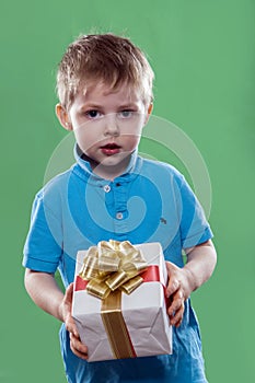 A little boy holding a gift box in his hands isolated on the green background