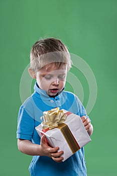 A little boy holding a gift box in his hands isolated on the green background