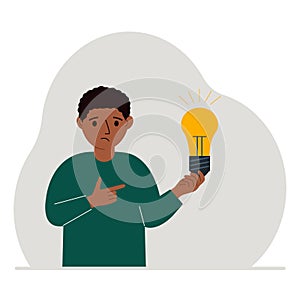 A little boy is holding a light bulb in his hand. Concept of idea, brainstorming, thinking, solution, eureka, bingo