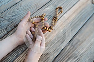 Little boy holding old wooden rosary.