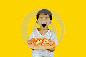 Little boy holding pizza isolated on yellow background