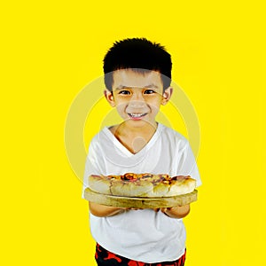Little boy holding pizza isolated on yellow background
