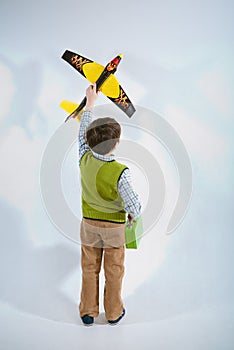 Little boy holding a plane model and handbag