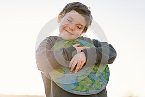 Little boy holding planet in hands against green spring background. Earth day