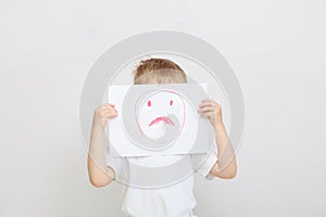 Little boy holding sad face mask