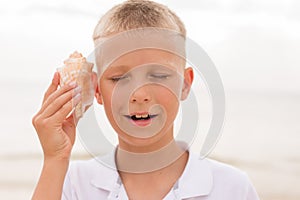 Little boy holding a seashell close to his ear