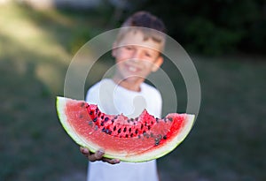 Little boy holding slice of watermelon depth of field