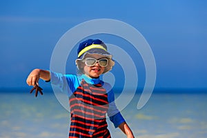 Little boy holding starfish at summer beach