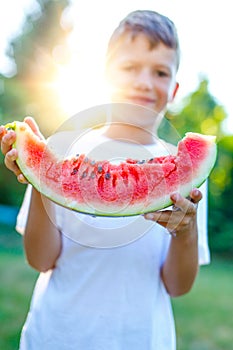 Little boy holding watermelon slice in sunset