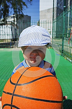 A little boy holds a basketball