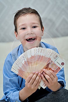 a little boy holds five-thousand-dollar bills in his hands and is happy.