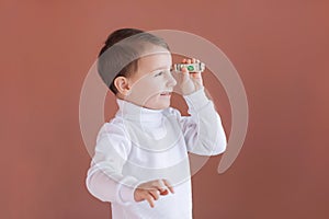 A little boy holds in his hands one dollar on a pink background, the joy of the first earnings