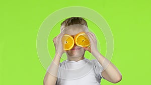 Little boy holds an orange slice and makes various grimaces. Green Screen