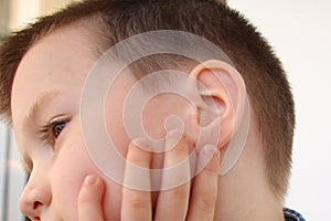 Little boy holds on to the ear, part of the face close-up, medical concept, hearing control, middle ear inflammation, otitis media