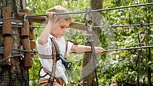 Little boy hooking safety rope before passing obstacles at rope adventure park. Kids sports, summer holiday, fun outdoors, scouts