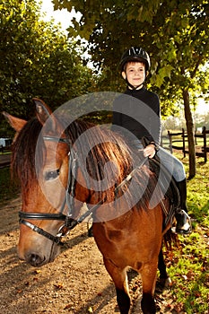 Little boy horseback riding in the green