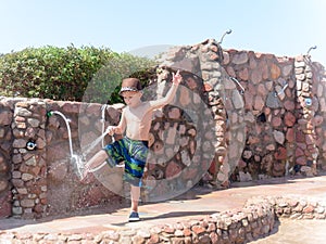 Little boy hosing off his shoes and feet