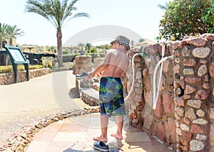 Little boy hosing off his shoes and feet
