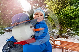 Little boy hug snowman in the park and smile