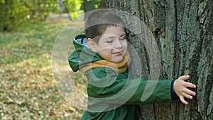 Little boy hugging a tree in the forest in autumn. A child's love for nature.